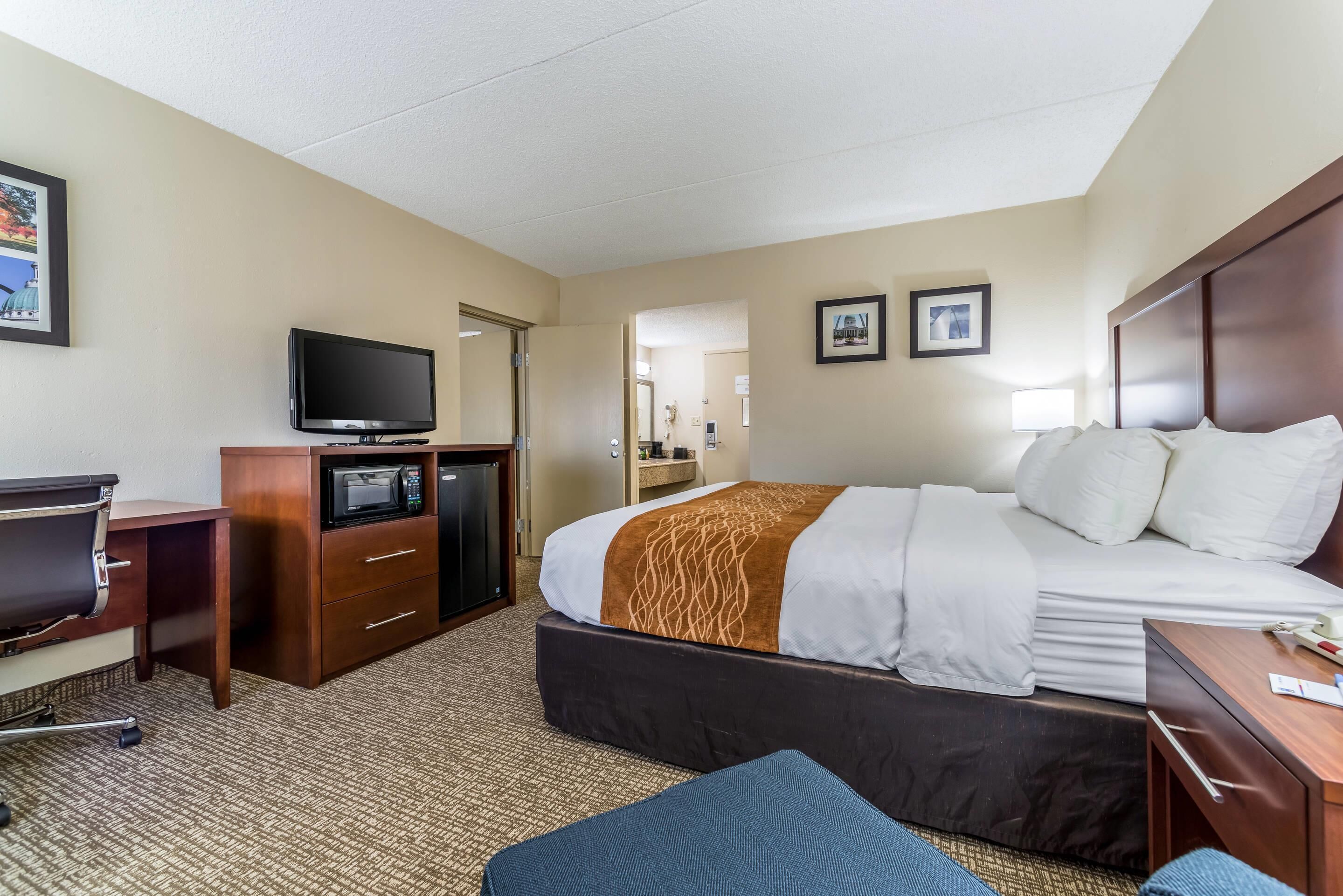 A hotel room with a bed, desk, TV, and a microwave.