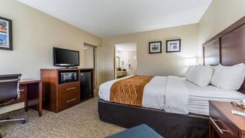 A hotel room with a bed, desk, TV, and a microwave.