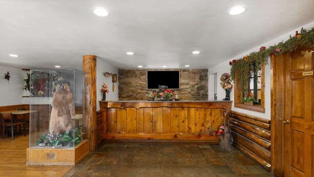 A lobby with a wooden reception desk, stone wall, and a bear statue. - Super 8 by Wyndham Jackson Hole (Jackson)