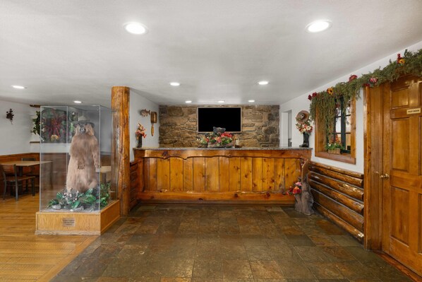 Un vestíbulo con un mostrador de recepción de madera, pared de piedra y una estatua de oso.