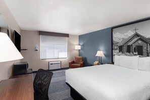 A hotel room with a bed, a desk, a chair, a lamp, a telephone, and a window. - Super 8 by Wyndham Jackson Hole (Jackson)