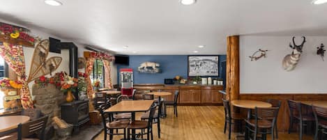 Un interior de restaurante con mesas y sillas de madera, una chimenea, arte decorativo en la pared y una pared de piedra.