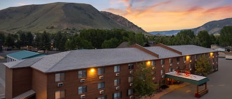 A hotel with multiple brick buildings, a covered outdoor area with seating, and a mountainous backdrop.