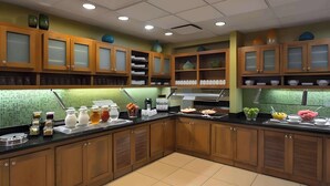 Una cocina con armarios de madera, encimera negra y varios utensilios.