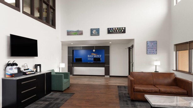 A modern lobby with a reception desk, a television, a leather sofa, and a coffee station. - Baymont by Wyndham Green Bay (Green Bay)