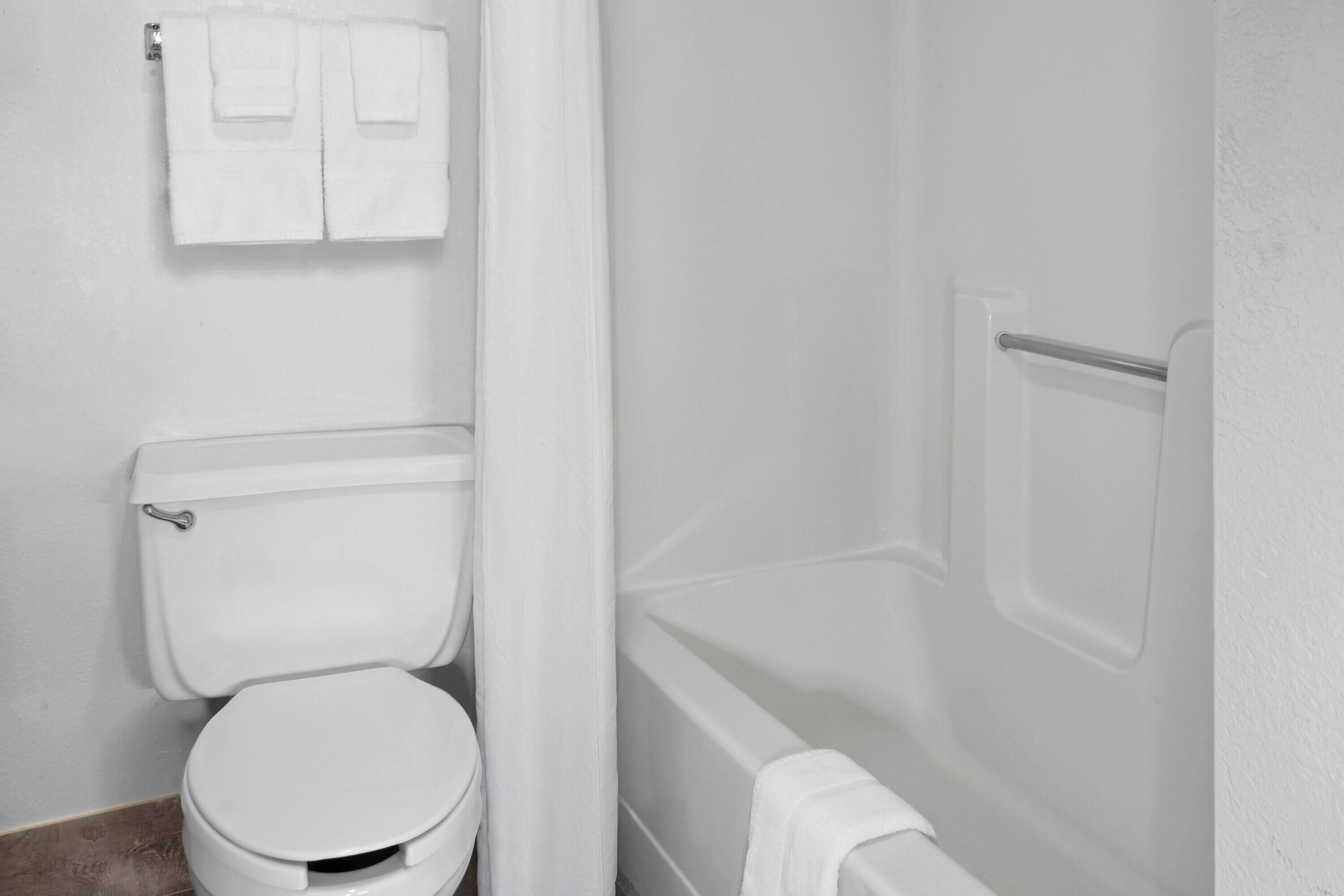 Un baño con inodoro, bañera y una toalla colgada en la pared.