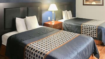 Een hotelkamer met twee bedden, een nachtkastje, een lamp en een ingelijst beeld aan de muur.