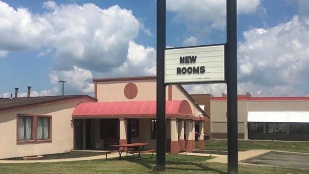 Un edificio con un cartel que dice 'NEW ROOMS' y una mesa de picnic al frente.