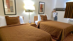 Ein Hotelzimmer mit zwei Betten, einem Nachttisch, einer Lampe und einem gerahmten Bild an der Wand.