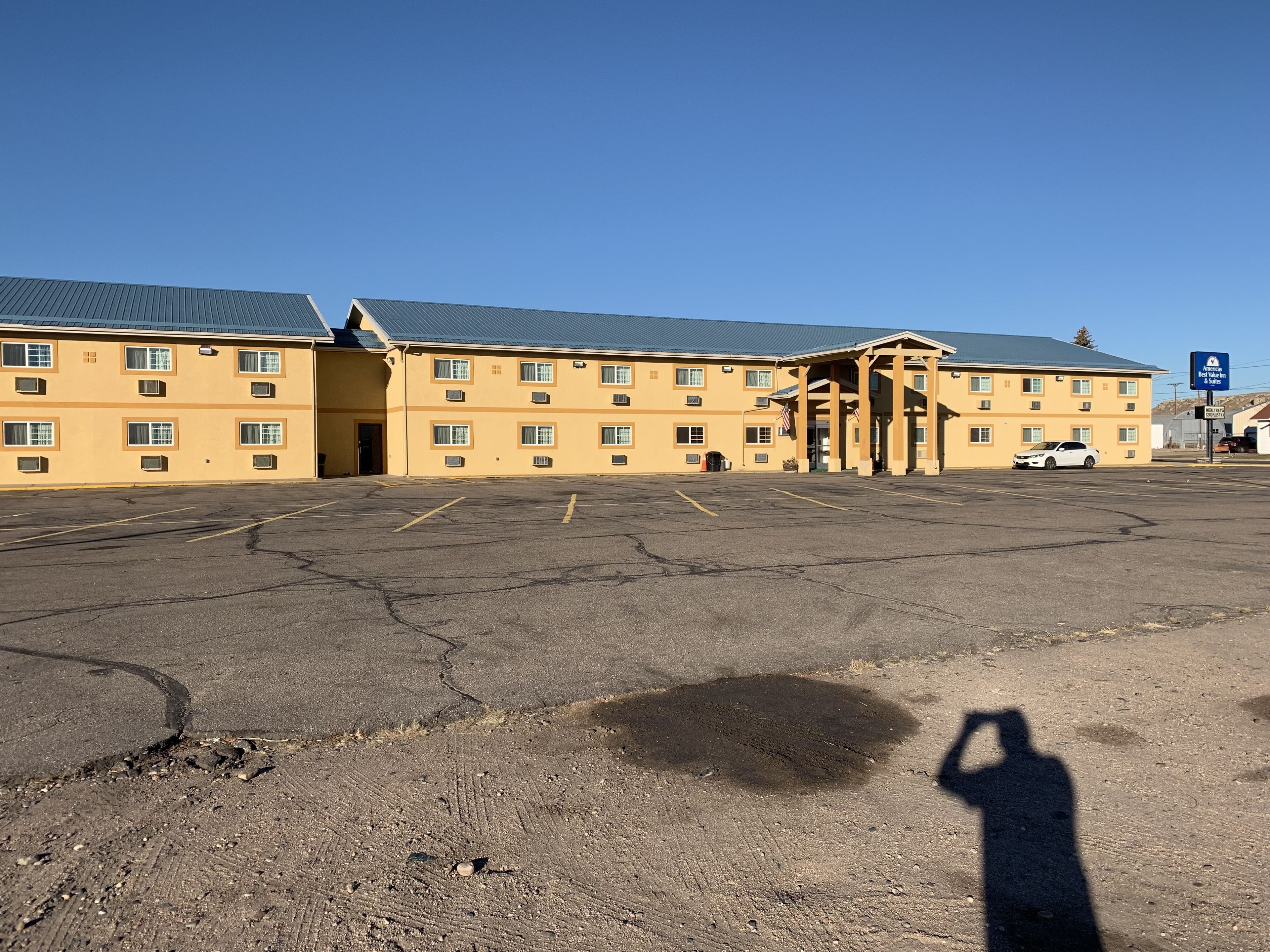 A large, yellow building with multiple windows and a parking lot in front.