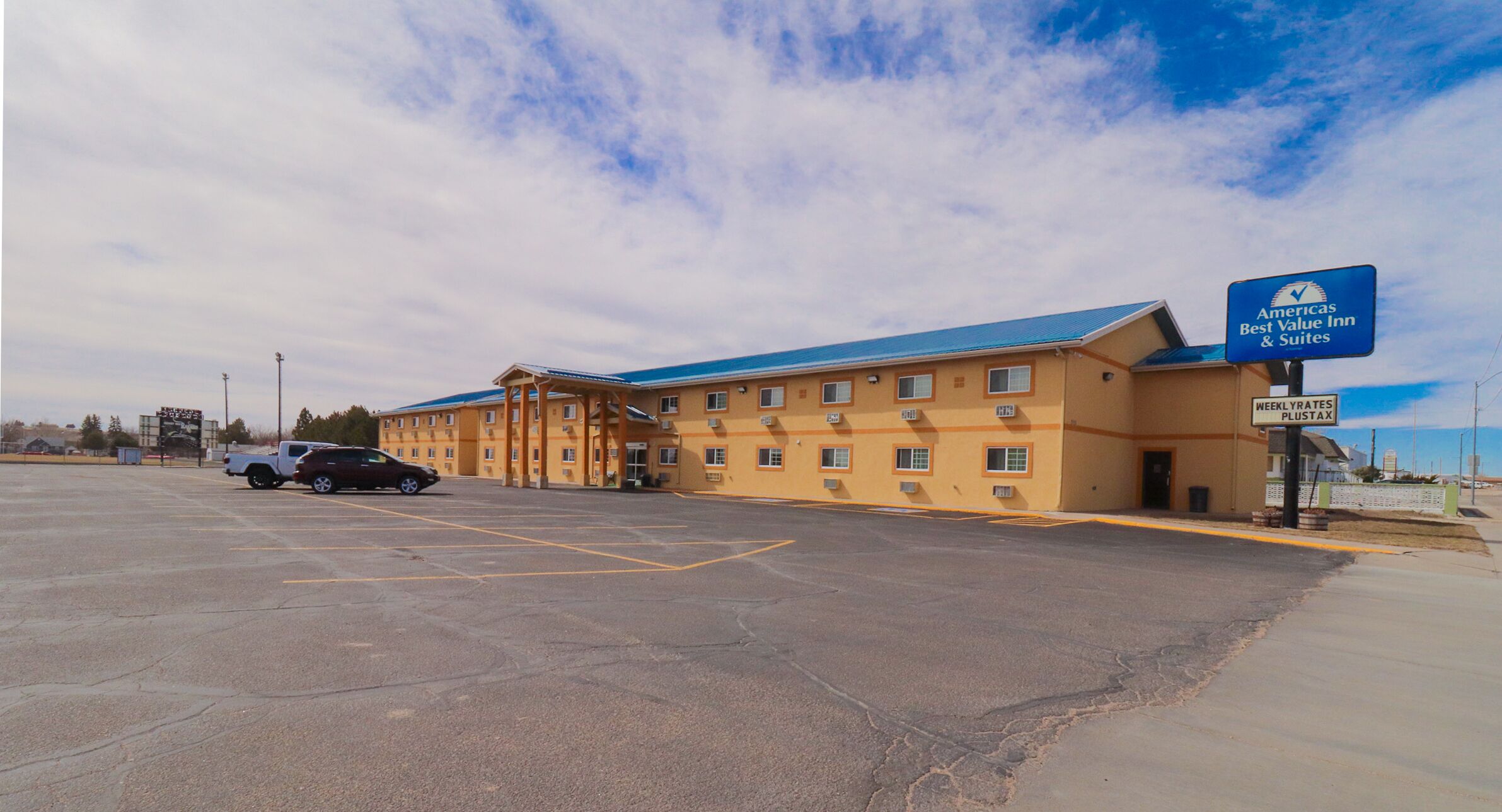 A Best Value Inn & Suites with a blue roof, a parking lot, and a sign indicating weekly rates.