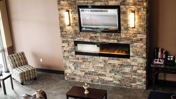A cozy living area with a stone fireplace, a television mounted on the wall, and a comfortable seating arrangement including a sofa and a chair.