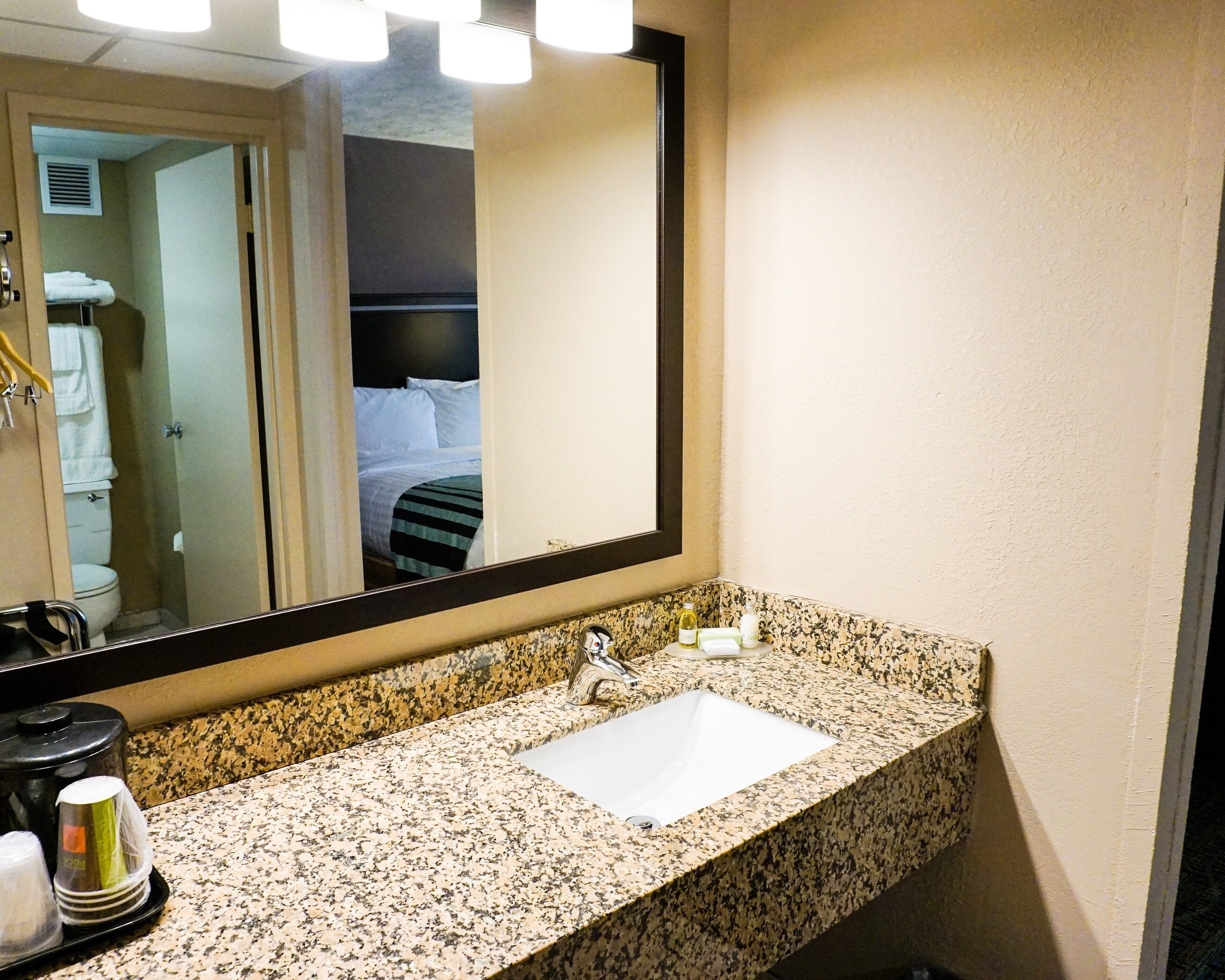 Un baño de hotel con encimera de granito, un lavabo y un espejo.