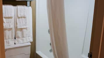 Un baño con inodoro, ducha con cortina y toallero con toallas dobladas.