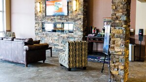 A lobby with a stone pillar, a fireplace, a television, a sofa, and a reception desk.