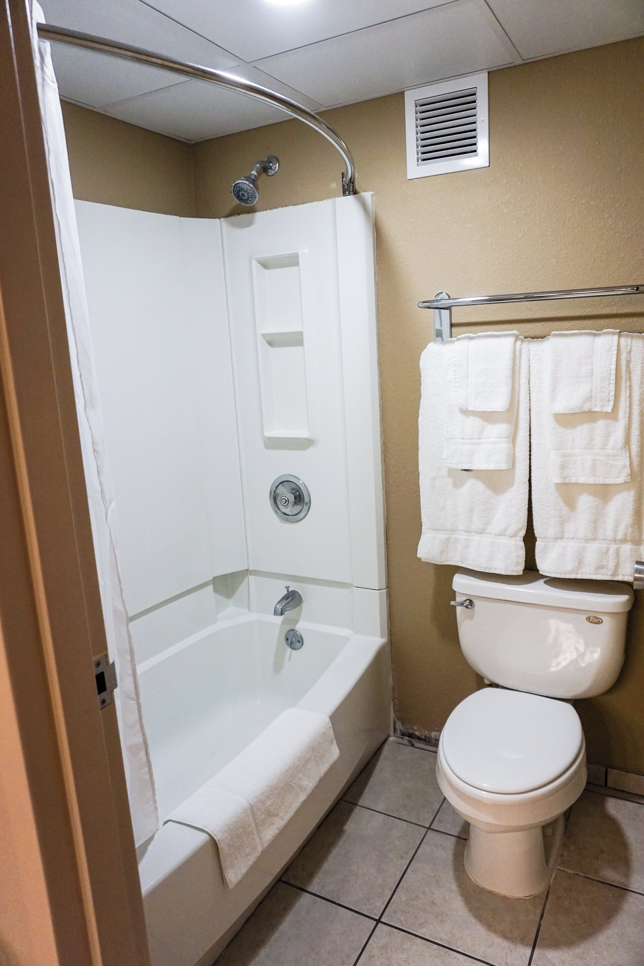 A bathroom with a bathtub, toilet, and a towel rack.
