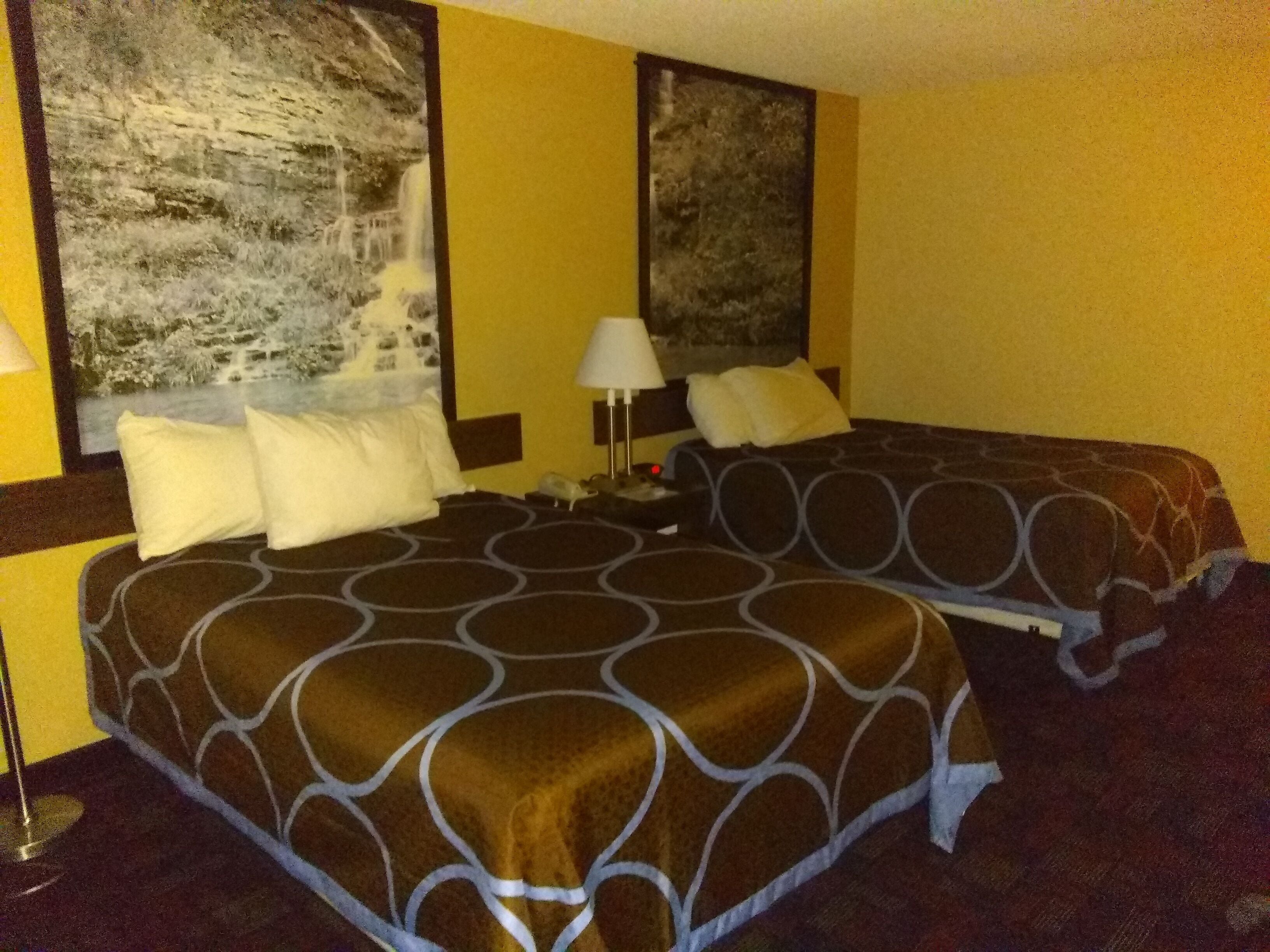 Ein Hotelzimmer mit zwei Betten, einem großen Fenster und einem Gemälde an der Wand.