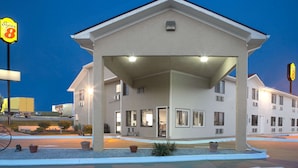 A motel with a covered parking area, multiple rooms, and a visible sign for a nearby Super 8 motel.