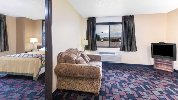 A hotel room with a bed, a sofa, a television, and a large window with curtains.