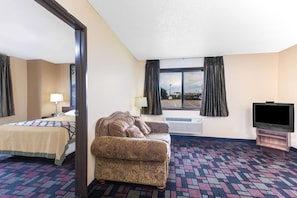 A hotel room with a bed, a sofa, a television, and a large window with curtains. - Super 8 by Wyndham Boonville (Boonville)