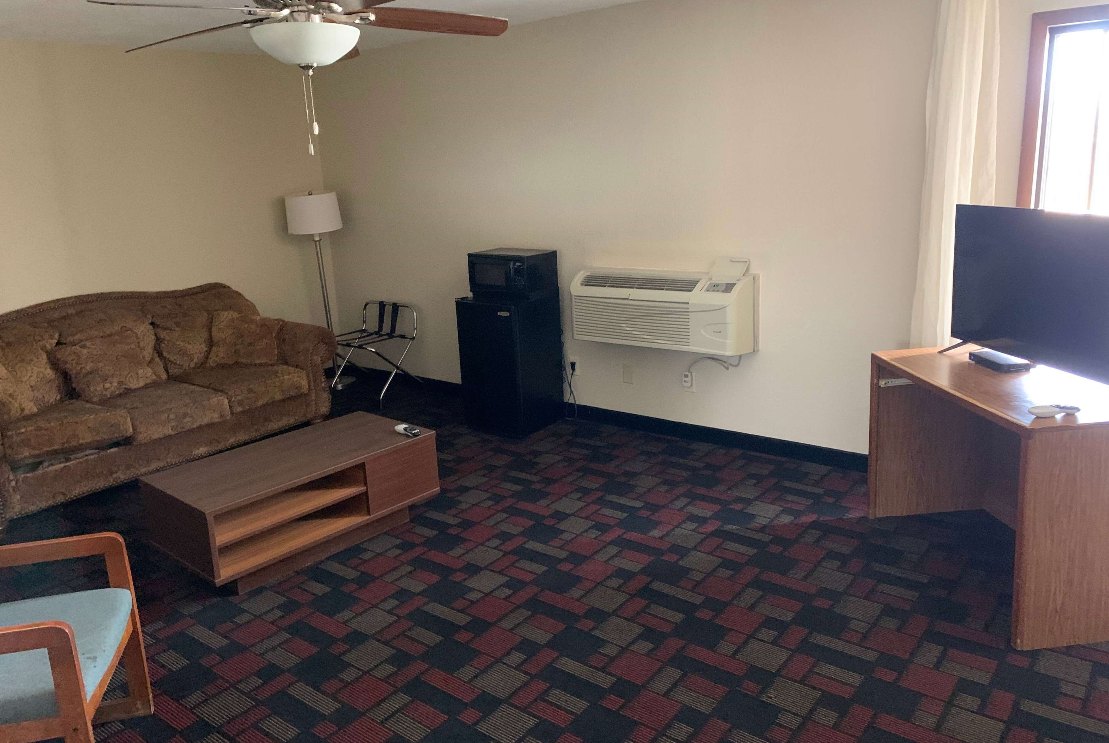 A living room with a brown sofa, wooden coffee table, and a TV on a wooden stand.
