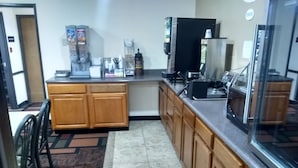 A kitchen with wooden cabinets, a refrigerator, a coffee machine, and a microwave.
