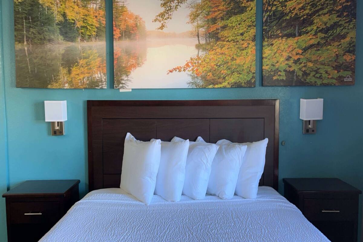 A bedroom with a large bed, two bedside tables, and a headboard.
