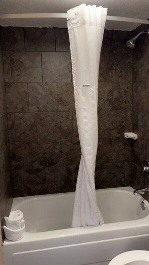A bathtub with a white shower curtain, a white towel, and a white soap dispenser.