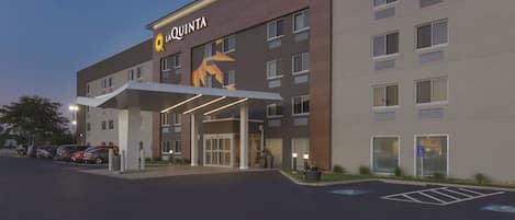 A hotel with a modern facade, a prominent logo, and a covered entrance.