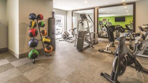Un gimnasio con equipo de ejercicio variado, incluyendo cintas de correr, bicicletas estáticas y una máquina de remo.