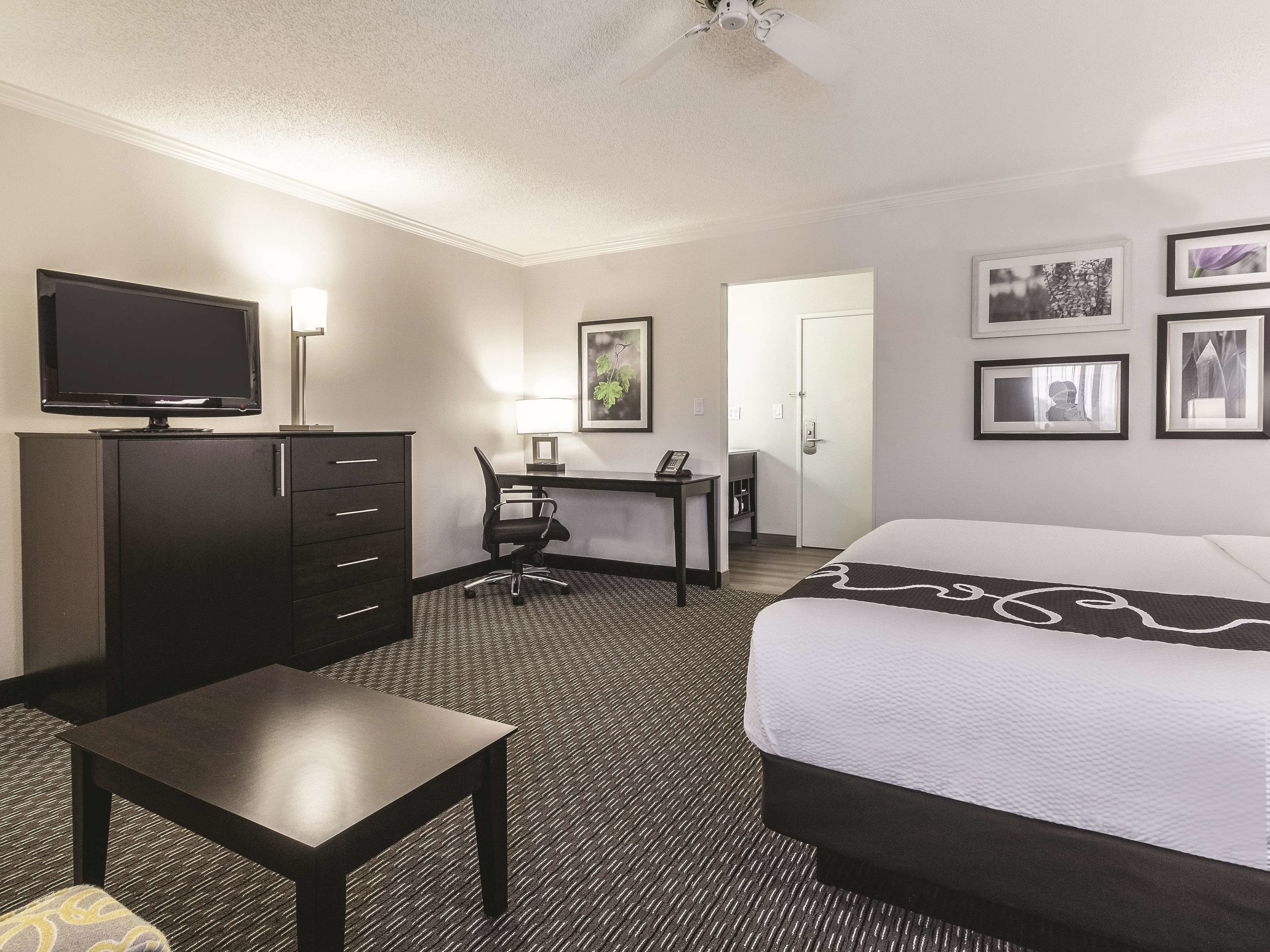 A hotel room with a bed, a desk, a chair, a television, and a wardrobe.