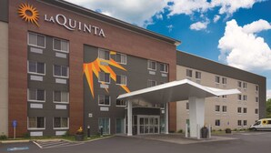 Hotel La Quinta con un llamativo logo de sol, una entrada cubierta y un estacionamiento.