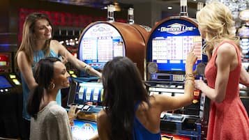 Eine Gruppe von Menschen spielt in einem Kasino an Spielautomaten.