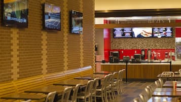 A restaurant with brick walls, multiple screens displaying menus, and a counter with a coffee machine.