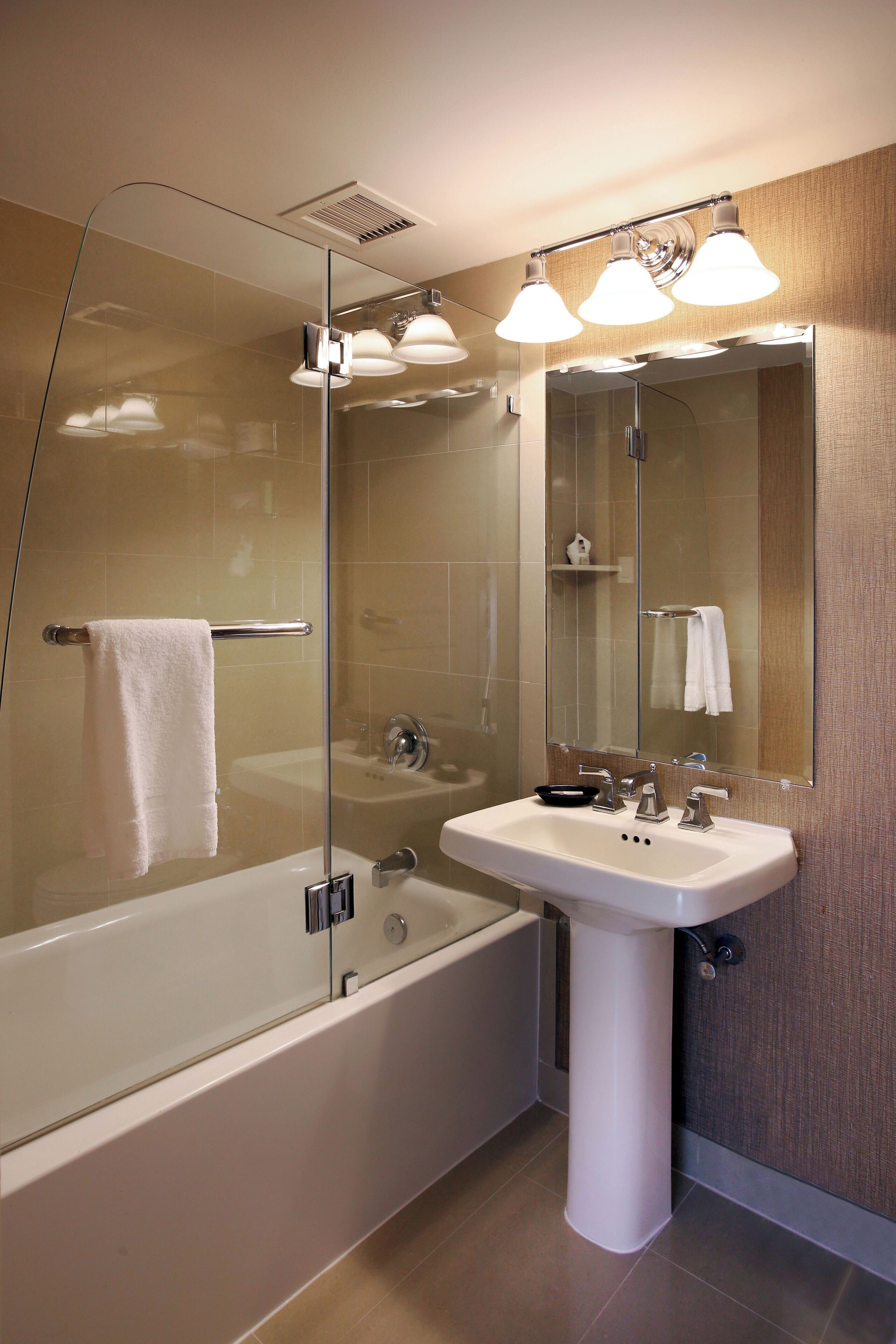 A modern bathroom with a glass-enclosed shower, a white sink, and a large mirror.