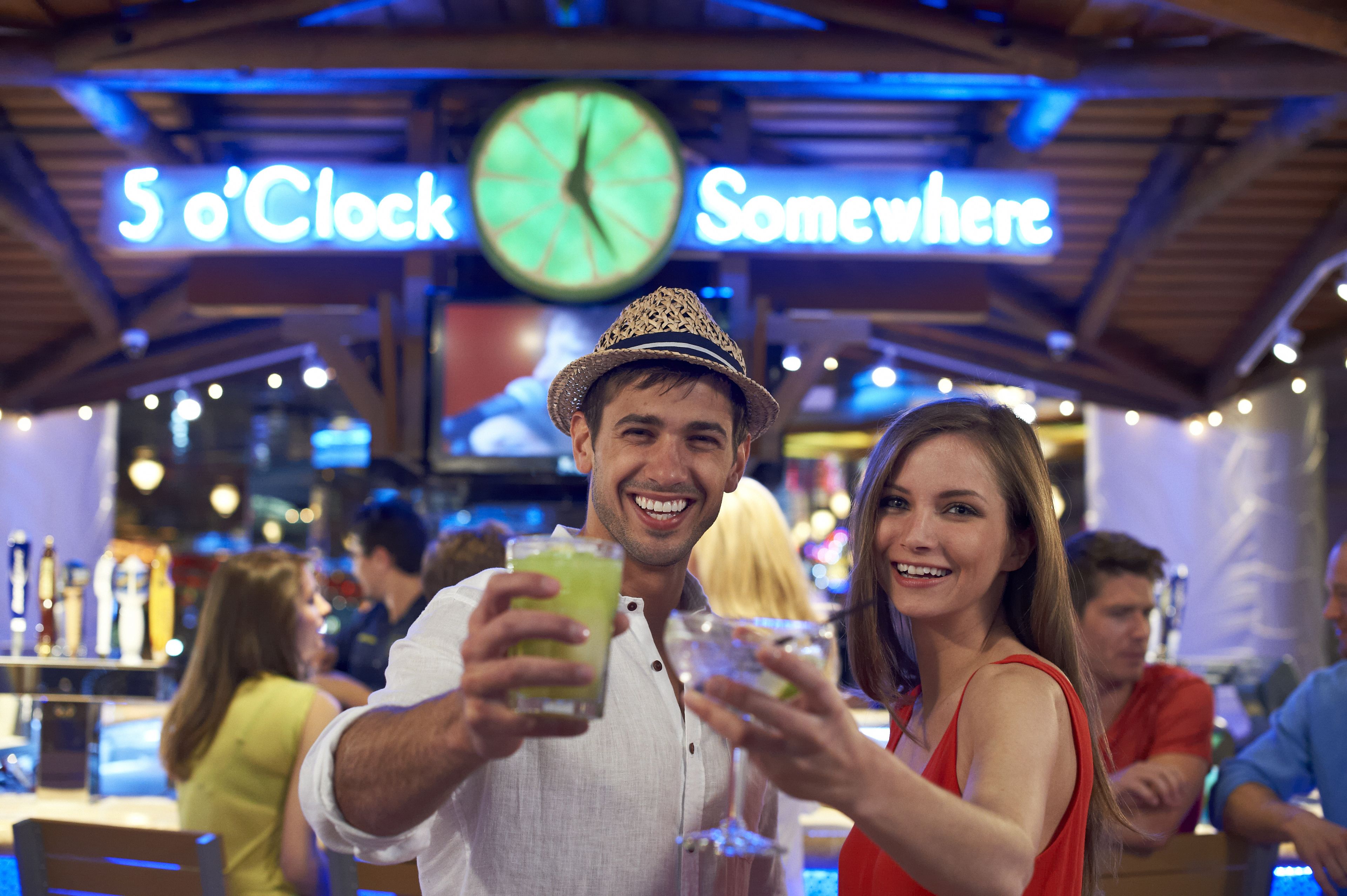 Zona de bar con un reloj y letreros de neón que dicen "5 en alguna parte".