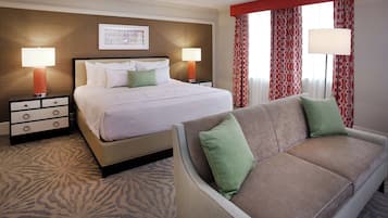 A hotel room with a bed, two bedside tables with lamps, a sofa, and a patterned carpet.