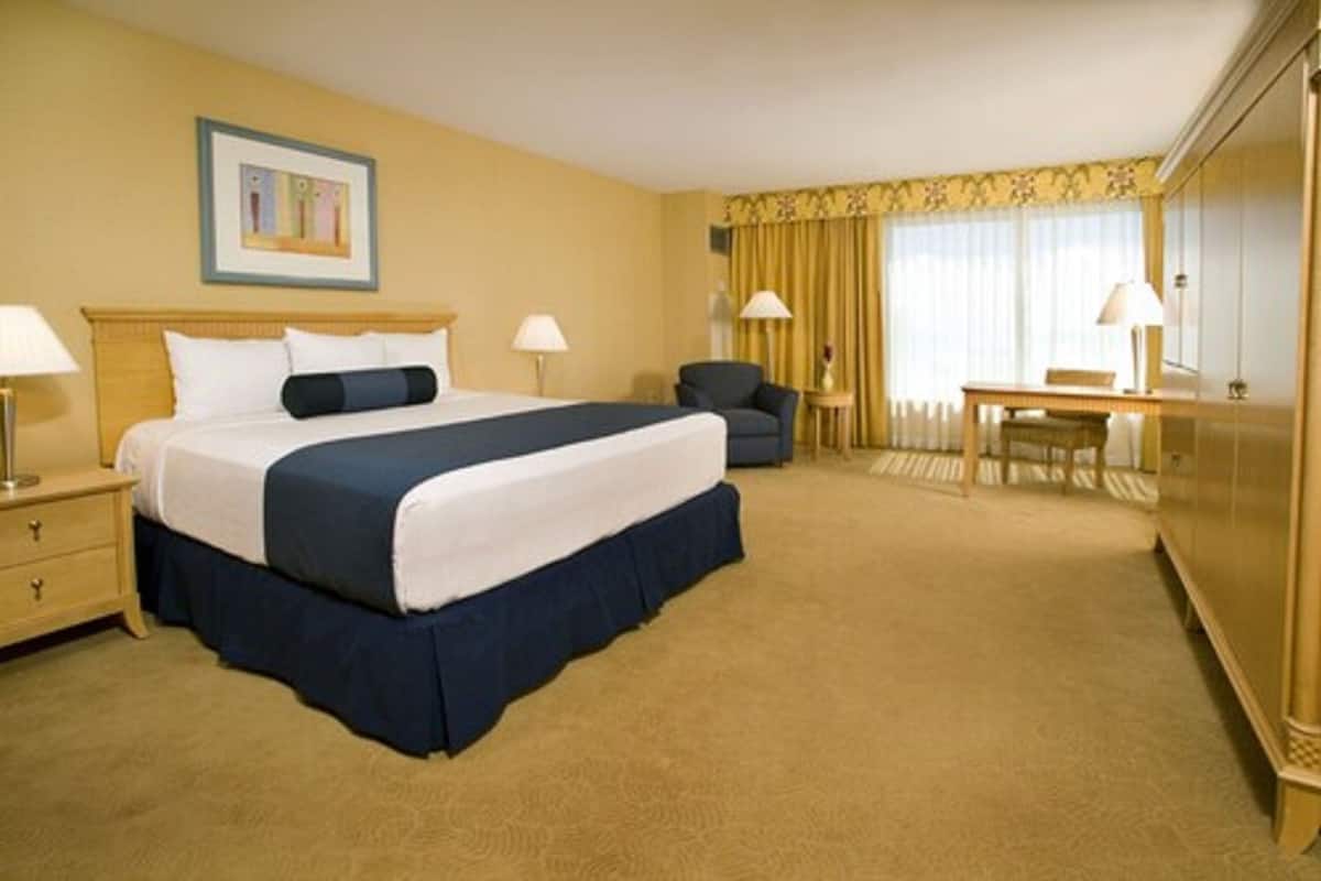 A hotel room with a large bed, two bedside tables, a desk, a chair, and a mirror.
