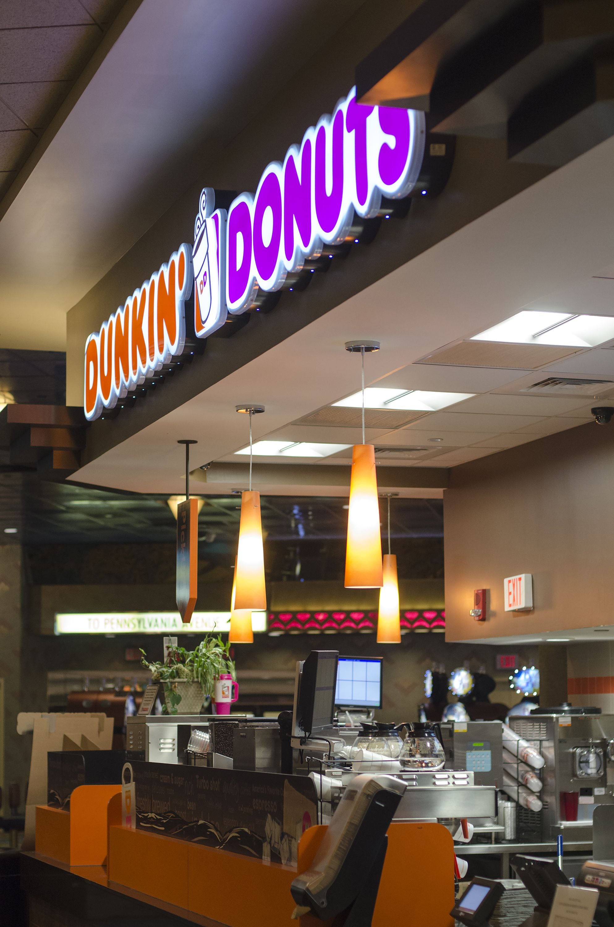 A Dunkin' Donuts with a bright sign, a coffee machine, and orange seating.