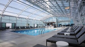 An indoor swimming pool with a glass ceiling, lounge chairs, and a clear view of the sky. - Resorts Casino Hotel Atlantic City (Atlantic City)