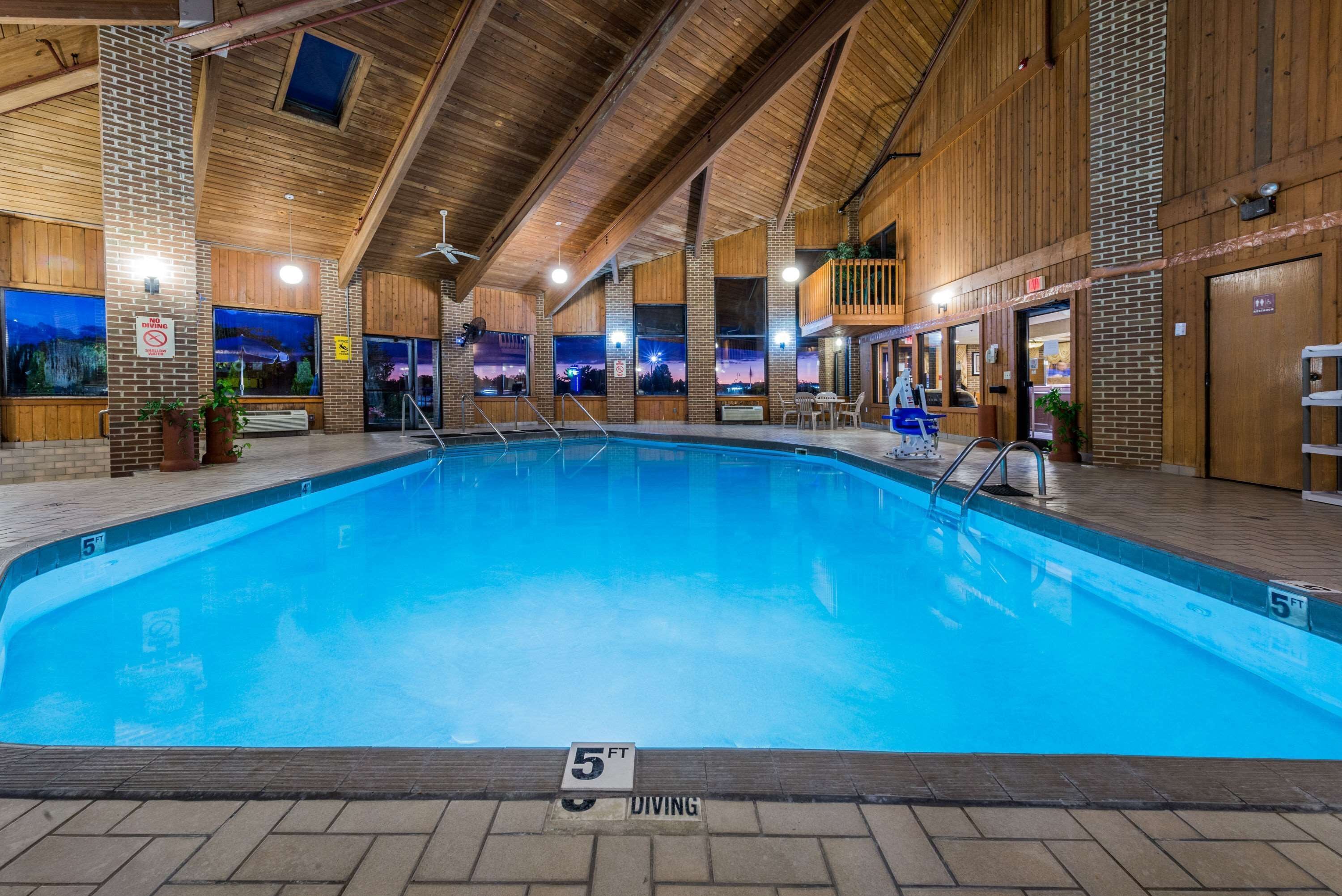 Una piscina interior con un trampolín de 1.5 metros, vigas de madera y paredes de ladrillo.