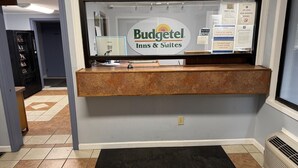 A reception desk at Budgettel Inns & Suites with a check-in counter, a computer, and various posted notices. - Budgetel Inn & Suites (Columbus)