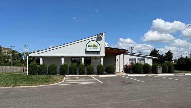 A Budgettel Inn & Suites with a parking lot and a clear blue sky. - Budgetel Inn & Suites (Columbus)