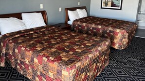 A hotel room with two beds, each with a patterned bedspread, a headboard, and a nightstand. - Budgetel Inn & Suites (Columbus)