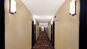 A hotel hallway with a carpeted floor, light fixtures on the walls, and doors on both sides. - Super 8 by Wyndham Joplin (Joplin)