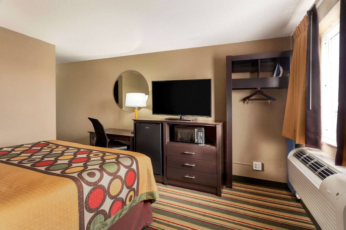 Hotelkamer met een bed, een bureau met een flatscreen televisie, een minibar, een magnetron, een verwarming en een kapstok.