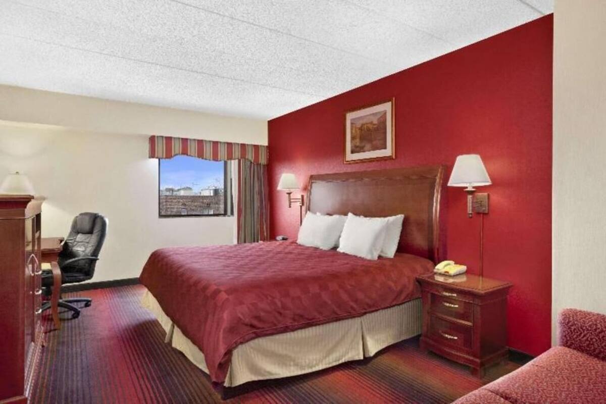 A hotel room with a large bed, a desk, a chair, and a window with a view.