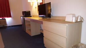 Ein Hotelzimmer mit Schreibtisch, Fernseher, Mikrowelle und Mülleimer.