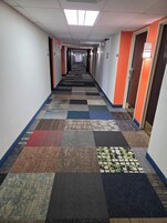 Pasillo de hotel con alfombra a cuadros, puertas a ambos lados y señal de salida.