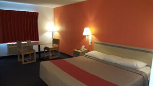 Ein Hotelzimmer mit einem Bett, einem Schreibtisch, zwei Sesseln, einem Telefon und zwei Wandlampen.
